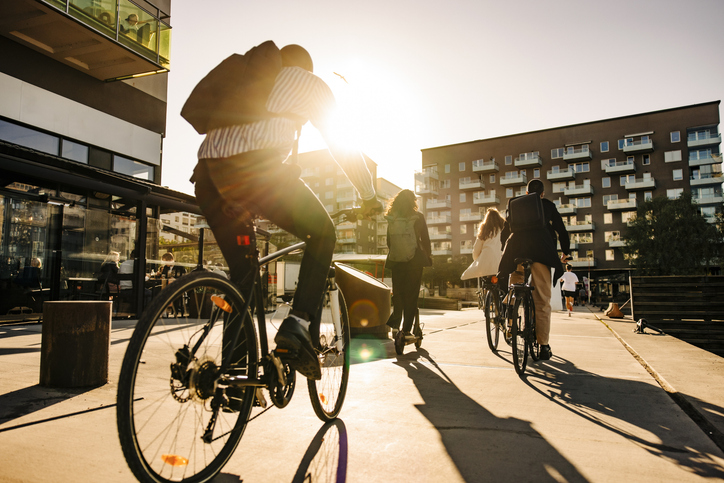 Business people commuting through bicycles at sunset
